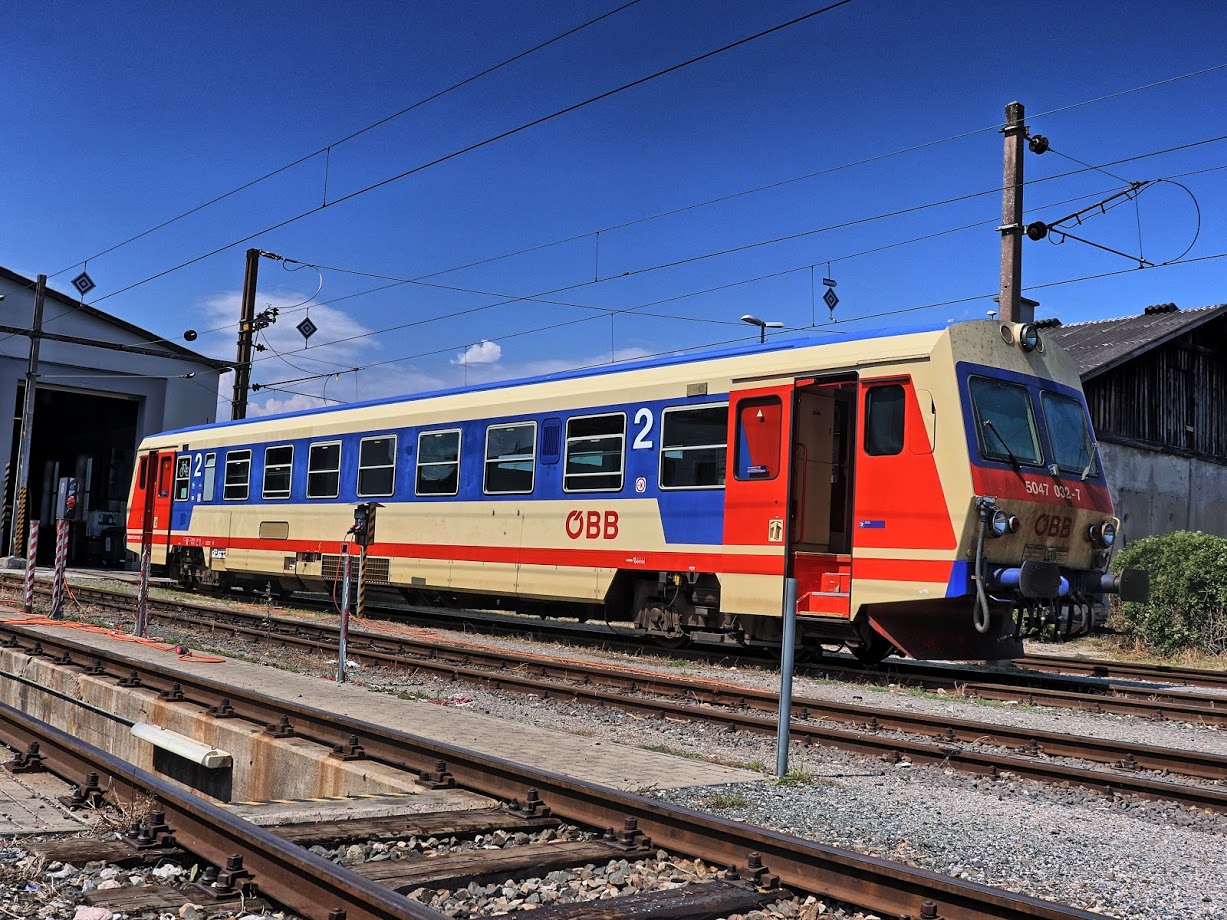 Alte Diesel-Fahrzeuge vom Typ ÖBB 5047 mit mehreren Stufen beim Einstieg.